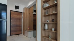 A modern kitchen with a black refrigerator, wooden cabinets, and a marble-tiled floor. - Centrally Located Cozy D&O Apartment (Skopje)