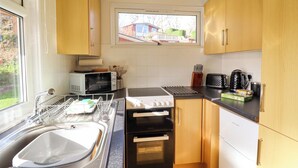 Een kleine keuken met een spoelbak, magnetron, broodrooster, oven en houten kastjes.