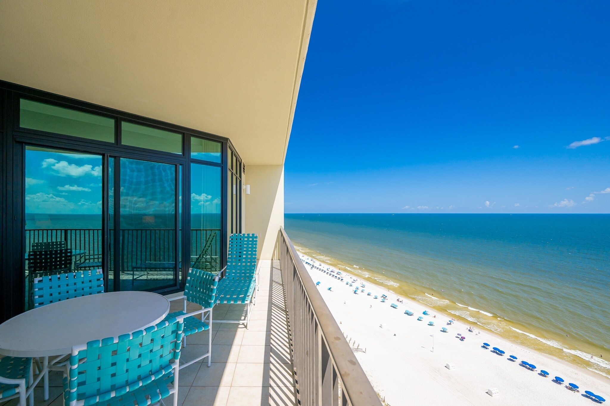 A balcony with a view of the beach, featuring a table and chairs.