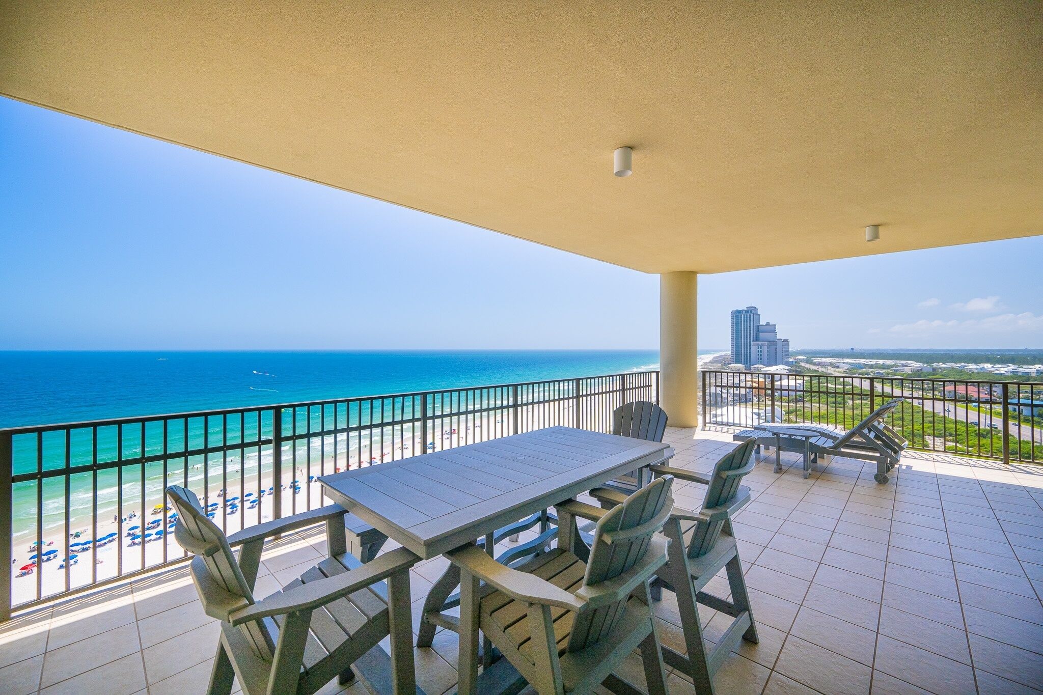 A balcony with a table and chairs overlooking the beach and ocean.