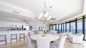 Una cocina moderna con armarios blancos, una isla central y un comedor con una mesa redonda y sillas.