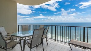 Ein Balkon mit Glastisch und Stühlen, der Blick auf das Meer geht.