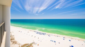 Blick auf einen Strand vom Balkon aus, mit blauem Himmel und Meer.