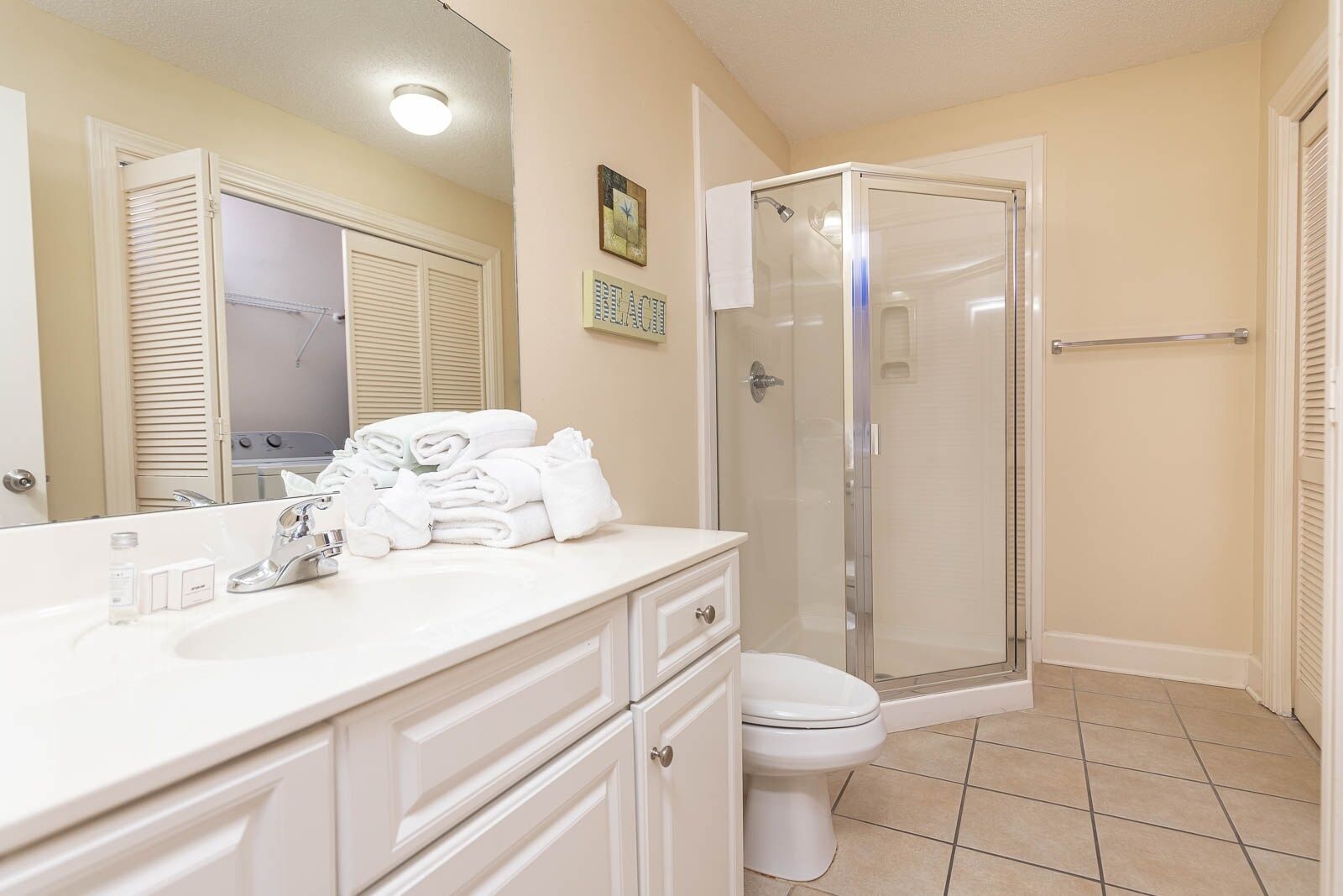 A bathroom with a shower, toilet, and vanity with towels.
