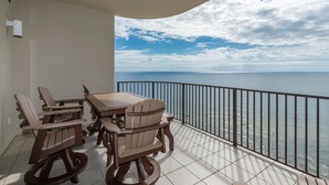 A balcony with a table and chairs, a view of the sea, and a railing. - Phoenix West 2106 3 Bedroom Condo (Orange Beach)