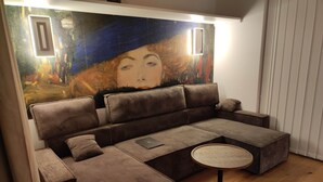 Una sala de estar moderna con un sofá modular, una mesa de centro redonda y un cuadro abstracto grande en la pared.