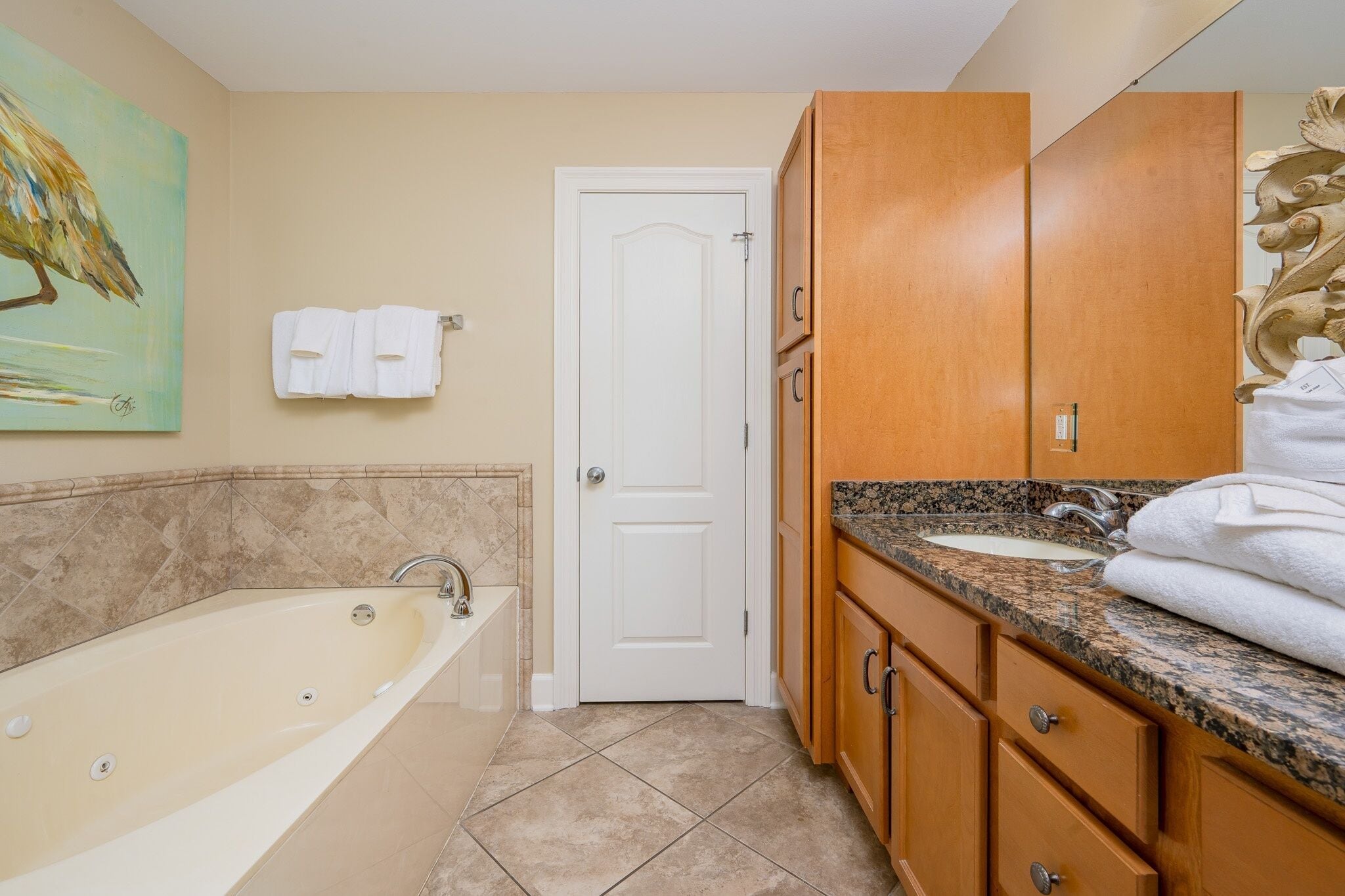 A bathroom with a bathtub, a sink, wooden cabinets, and a door.
