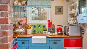 A kitchen with blue cabinets, a red refrigerator, and various kitchen items. - Y Golchdy (Llangadog)