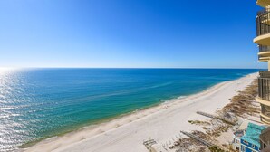 Un hôtel situé en bord de mer, offrant une vue sur l’océan, une plage de sable et un ciel dégagé.