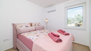 A bedroom with a bed, a bedside lamp, an air conditioner, and a window with a view. - Moderne Ferienwohnung mit Meerblick, überdachter Terrasse & Whirlpool (Dramalj)