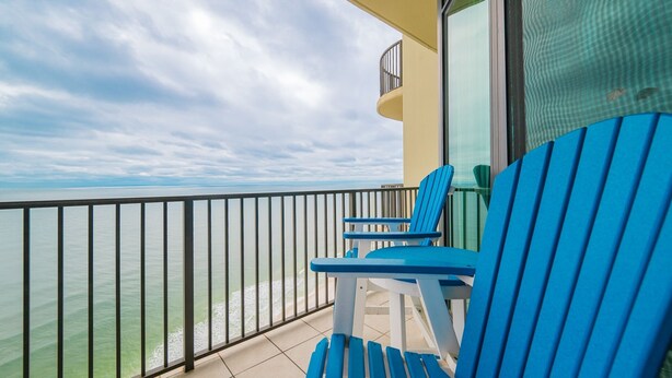 A balcony with blue chairs and a view of the sea. - Phoenix West 2607 3 Bedroom Condo (Orange Beach)