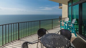 A balcony with a view of the ocean, two chairs, and a table. - Phoenix West 2505 3 Bedroom Condo (Orange Beach)