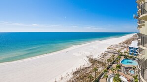 Uitzicht op het strand vanaf een balkon van een hotel, met een zwembad en een terras.