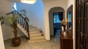 A staircase with a wooden handrail, a potted plant, and a small table with a vase. - Rural Villa with Private Pool near Vilamoura (Quarteira)