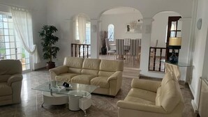A spacious living room with a beige sofa, a glass coffee table, and a potted plant. - Rural Villa with Private Pool near Vilamoura (Quarteira)