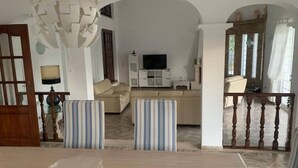 A living room with a sofa, TV, and a staircase leading to another level. - Rural Villa with Private Pool near Vilamoura (Quarteira)
