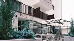Un hotel de diseño moderno, con fachada de vidrio, asientos al aire libre y un cartel que indica el nombre 'brenner hotel'.