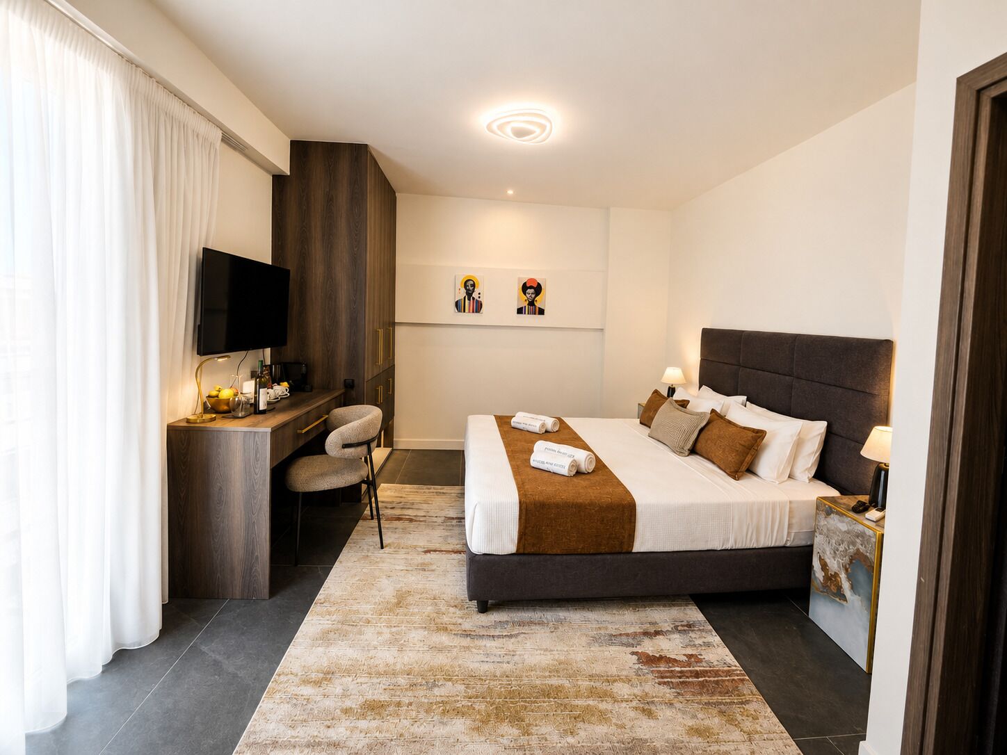 A modern hotel room with a bed, desk, and seating area.