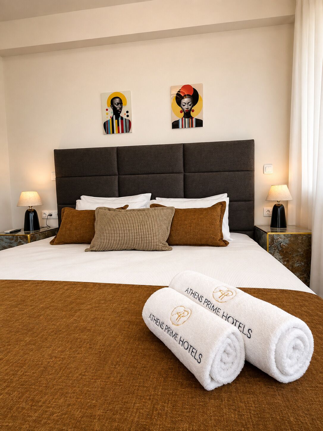 A hotel room with a large bed, two bedside lamps, a headboard, and artwork on the wall.
