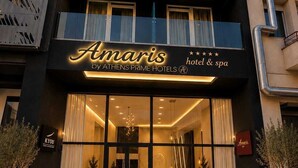 Entrada de un hotel con fachada moderna, puertas de cristal grandes y un cartel que dice 'Amaris by ATHENS PRIME HOTELS'.