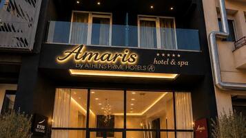 A hotel entrance with a modern facade, large glass doors, and a sign for 'Amaris by ATHENS PRIME HOTELS'.