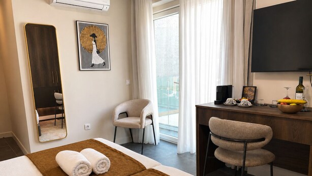 A hotel room with a bed, a desk with a computer, a chair, a large mirror, and a painting on the wall. - Amaris Hotel & Spa by Athens Prime Hotels (Athens)