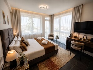 A modern hotel room with a large bed, a desk with a flat-screen TV, and a view of the outdoors. - Amaris Hotel & Spa by Athens Prime Hotels (Athens)