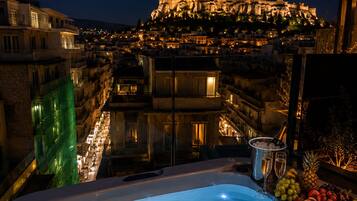 A hot tub with a cityscape view, including a prominent ancient structure illuminated at night.