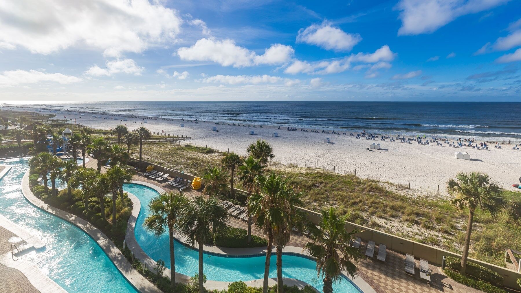 A resort with a swimming pool, beach, and ocean view.