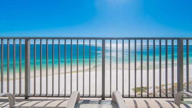 A balcony with a metal railing overlooking a beach with clear turquoise water and a sandy shore. - The Oasis 1503 Formerly Phoenix West Ii 1503 3 Bedroom Condo (Orange Beach)