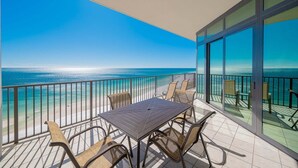 A balcony with a table and chairs, overlooking a beach and ocean. - The Oasis 1503 Formerly Phoenix West Ii 1503 3 Bedroom Condo (Orange Beach)