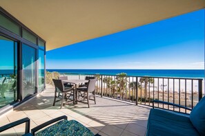 A balcony with a table and chairs, a sofa, and a view of the beach and ocean. - Phoenix West 302 3 Bedroom Condo (Orange Beach)