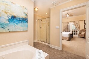 A bathroom with a bathtub, a glass shower enclosure, and a large abstract painting on the wall. - The Oasis 606 Formerly Phoenix West Ii 606 3 Bedroom Condo (Orange Beach)