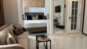 A modern hotel room with a bed, a sofa, a small table, and a TV.