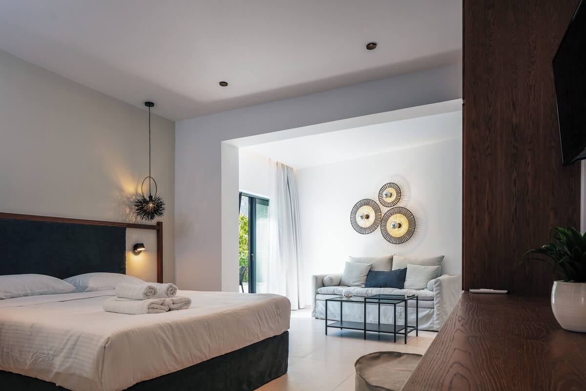 A modern bedroom with a bed, bedside table, and a view of the living area.