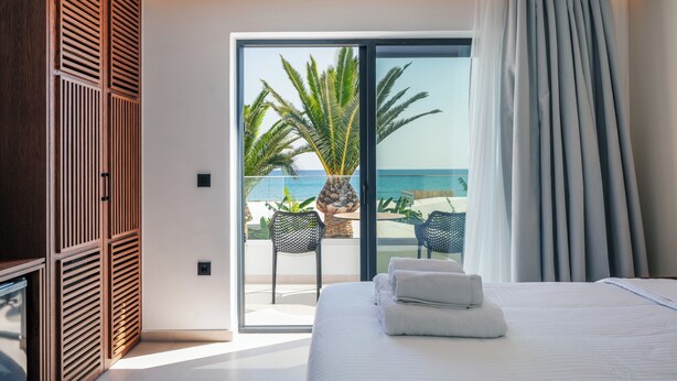 A bedroom with a bed, a sliding glass door to a balcony, and a view of the ocean. - Del Mare (Bali)