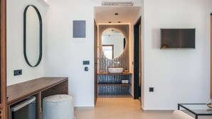 A modern bathroom with a vanity, sink, and mirror. There is a television mounted on the wall and an air conditioning unit above. - Del Mare (Bali)