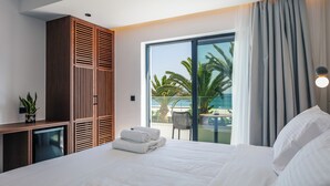 A modern hotel room with a bed, a small desk, a wardrobe, and a balcony with a view of palm trees. - Del Mare (Bali)