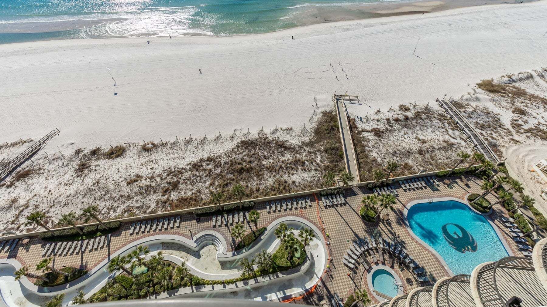 A resort with a beach, a pool, and a winding pathway.
