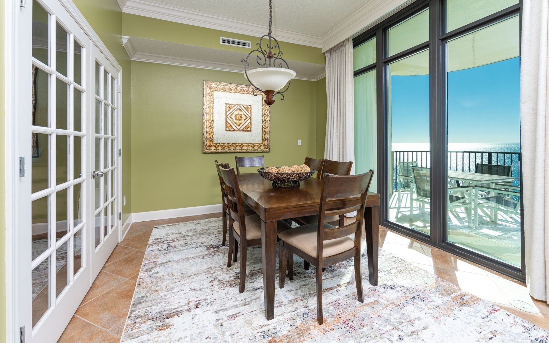 A dining area with a table, chairs, a chandelier, and a large window with a view.