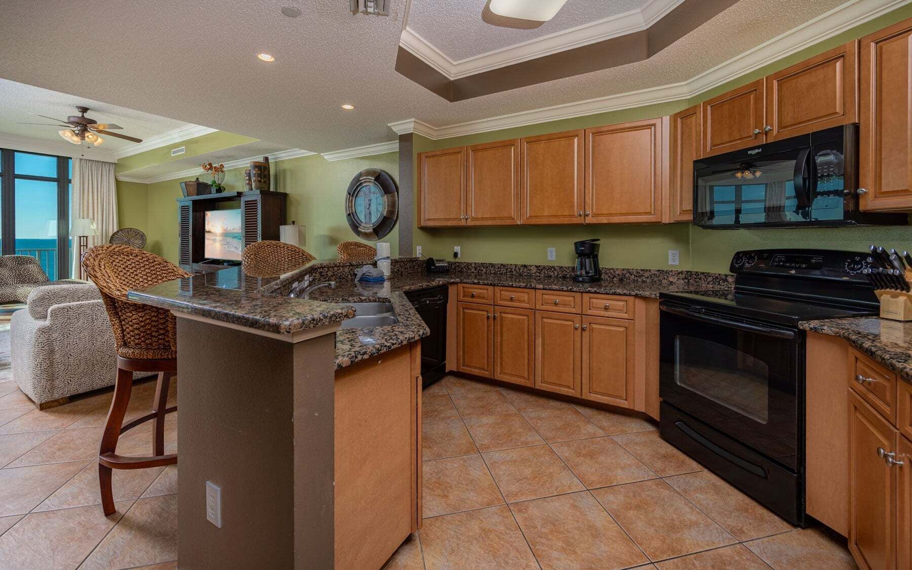 A kitchen with wooden cabinets, a granite countertop, and a black stove.