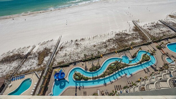 A resort with a large pool area, a beach, and a lifeguard tower. - Phoenix West 1609 4 Bedroom Condo (Orange Beach)