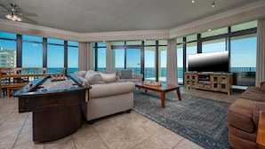 A spacious living area with a pool table, a sofa, a coffee table, and a TV. - Phoenix West 1609 4 Bedroom Condo (Orange Beach)
