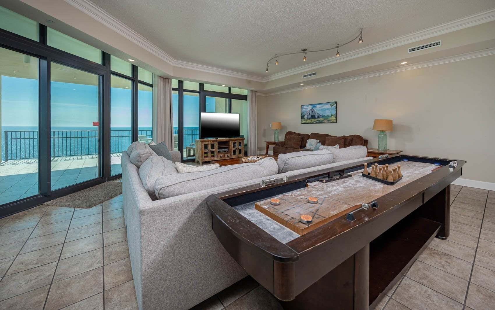 A spacious living room with a foosball table, a large sofa, and a television.