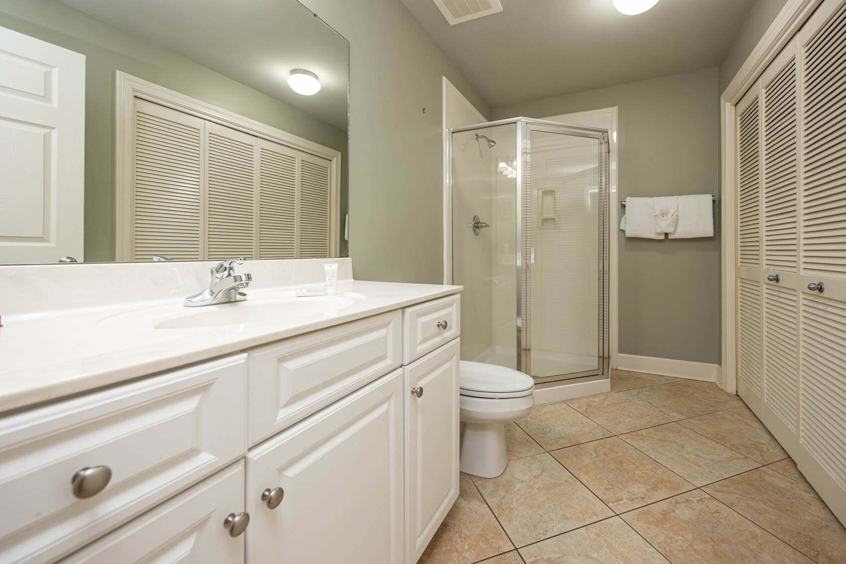 A bathroom with a shower, toilet, and vanity with drawers.