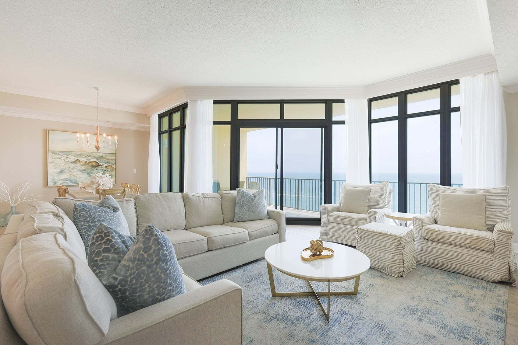 A spacious living room with a large sectional sofa, a round coffee table, and a striped armchair.