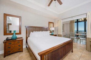 Ein Hotelzimmer mit einem großen Bett, einem Holzkopfende, zwei Nachttischen mit Lampen, einem Spiegel und einem Balkon mit Sitzgelegenheit.