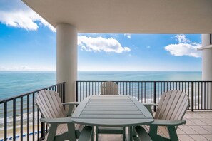 Ein Balkon mit Tisch und Stühlen mit Blick auf den Ozean.