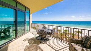 Un balcon avec une table et des chaises, un canapé et une vue sur la plage et l’océan.