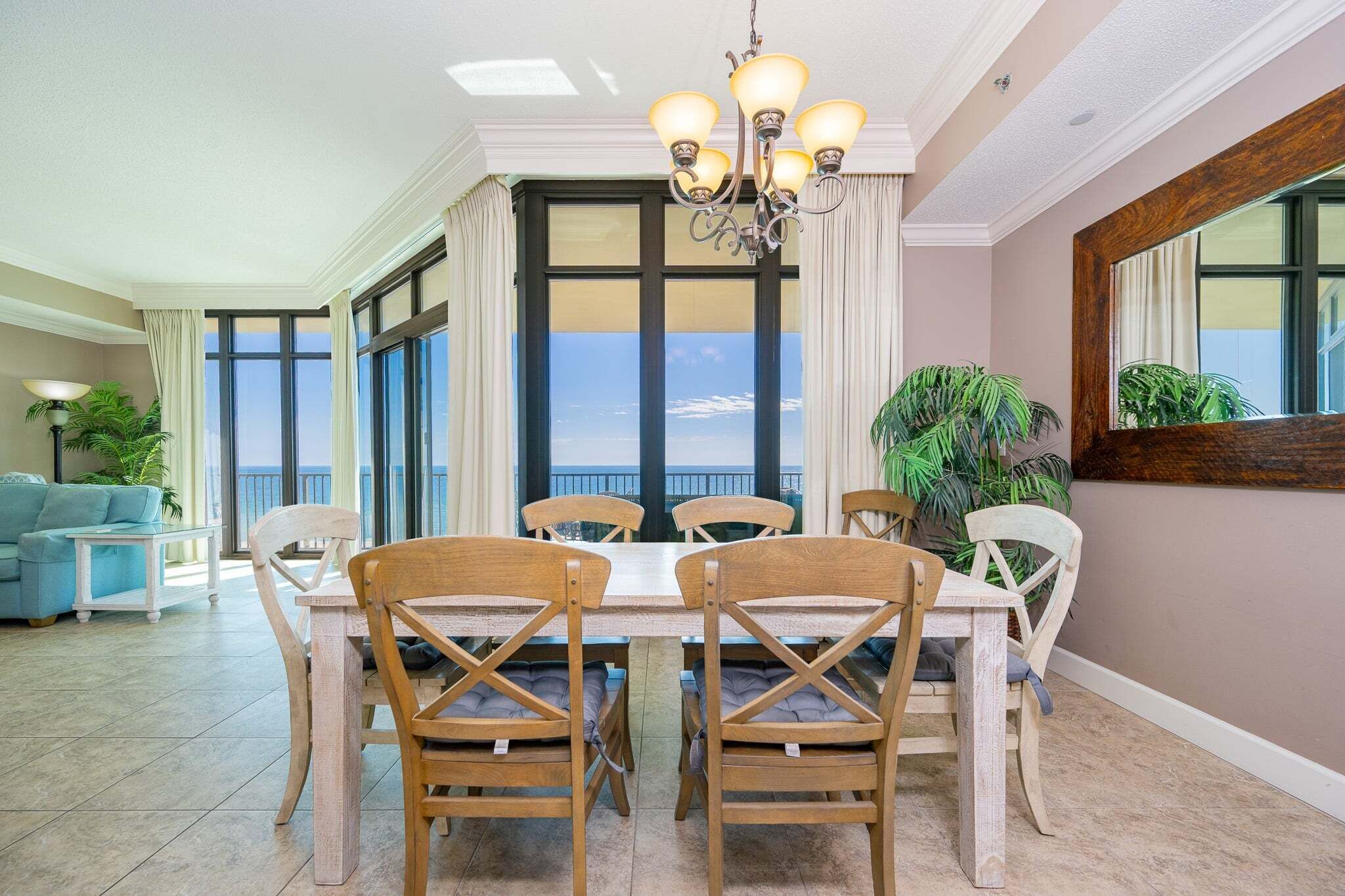 Un espace repas comprenant une table et des chaises, un lustre, de grandes fenêtres et une vue sur le ciel.